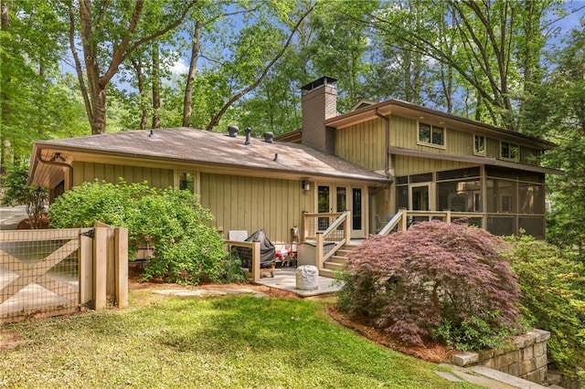 rear view of house featuring a yard, a chimney, and a sunroom