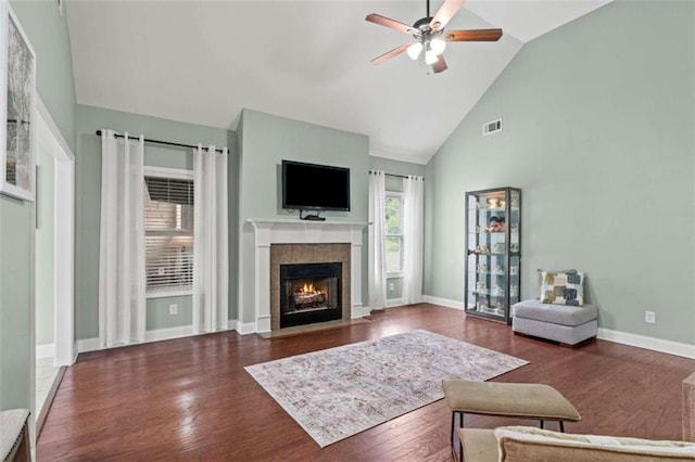 living room featuring a ceiling fan, wood finished floors, a tile fireplace, high vaulted ceiling, and baseboards