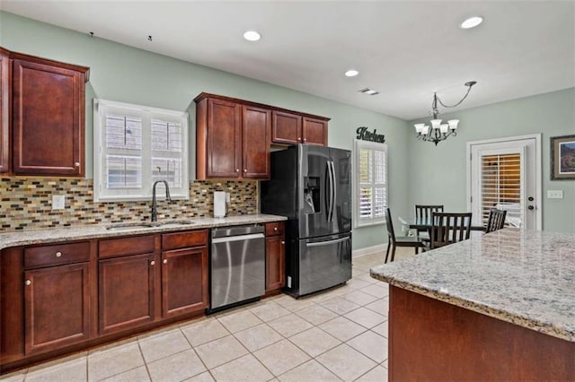 kitchen featuring appliances with stainless steel finishes, a sink, decorative backsplash, a chandelier, and light tile patterned floors