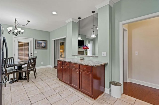 kitchen featuring light tile patterned flooring, decorative light fixtures, light stone countertops, a chandelier, and baseboards