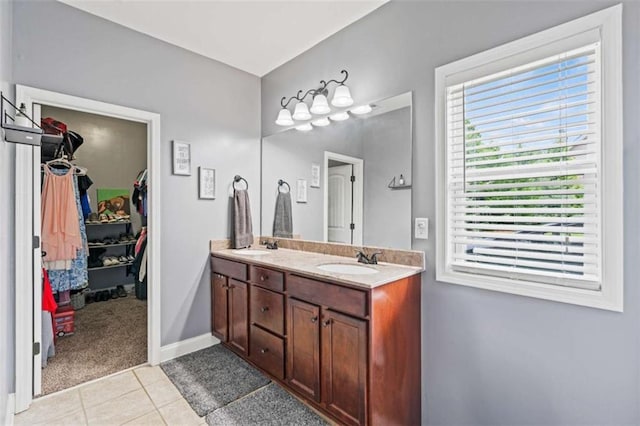 bathroom with double vanity, tile patterned flooring, a walk in closet, and baseboards