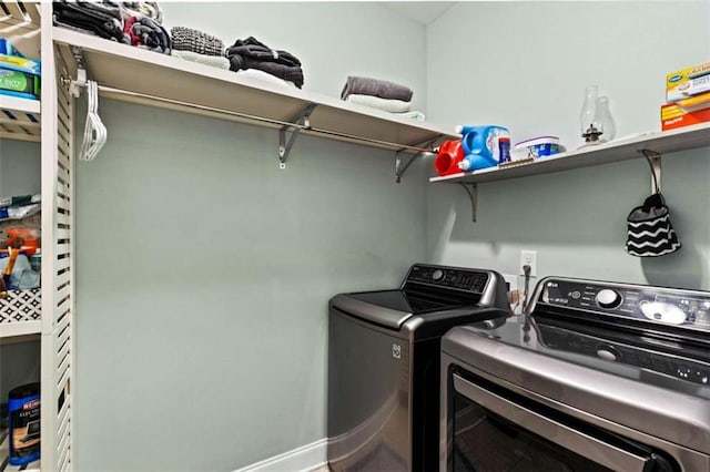 clothes washing area with independent washer and dryer and baseboards