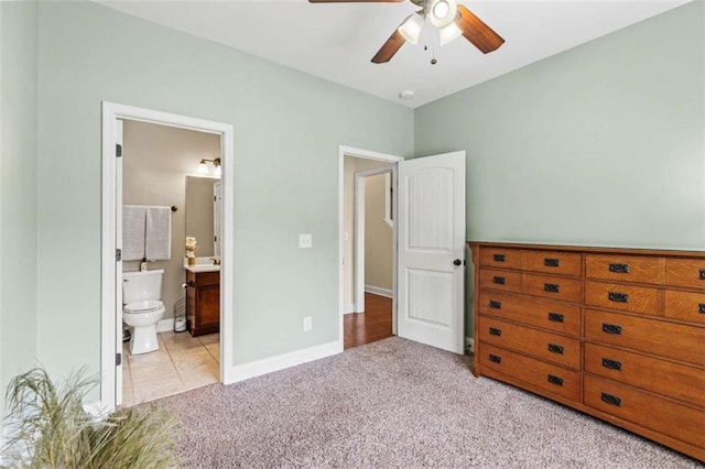 carpeted bedroom featuring baseboards, connected bathroom, and a ceiling fan