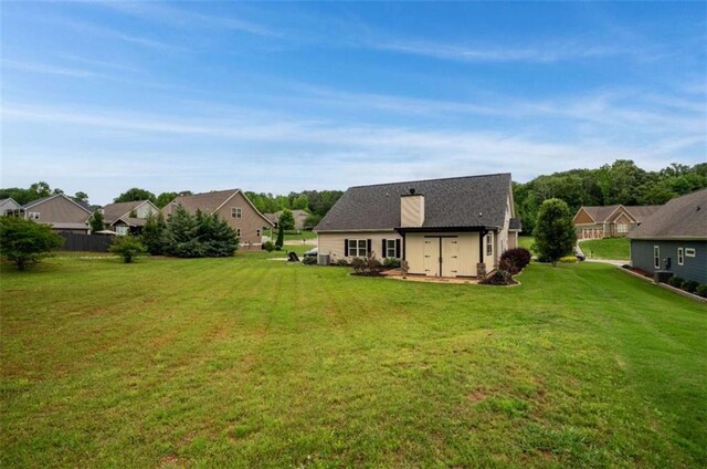 view of grassy yard with a residential view and an outdoor structure