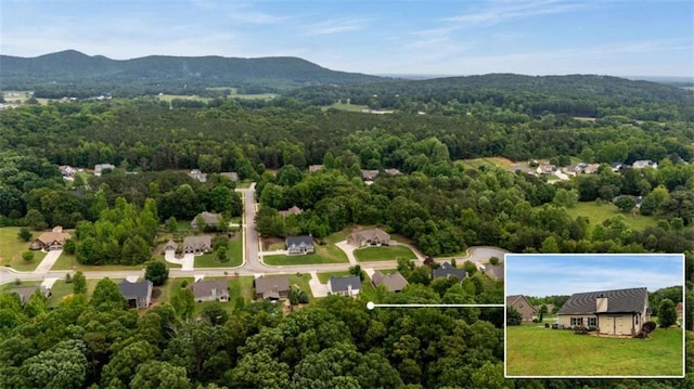 aerial view of property and surrounding area with property parcel outlined, a forest, and a mountainous background