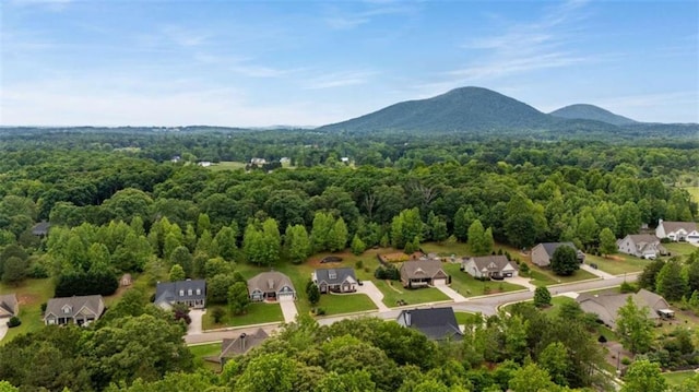 aerial view of residential area featuring a forest and a mountainous background