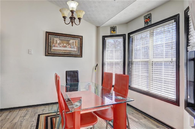 dining room featuring baseboards, a textured ceiling, an inviting chandelier, and wood finished floors