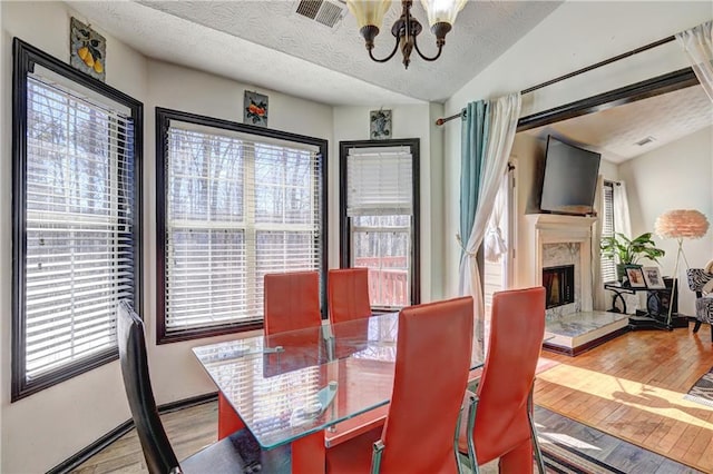 dining room with visible vents, wood finished floors, plenty of natural light, and a chandelier