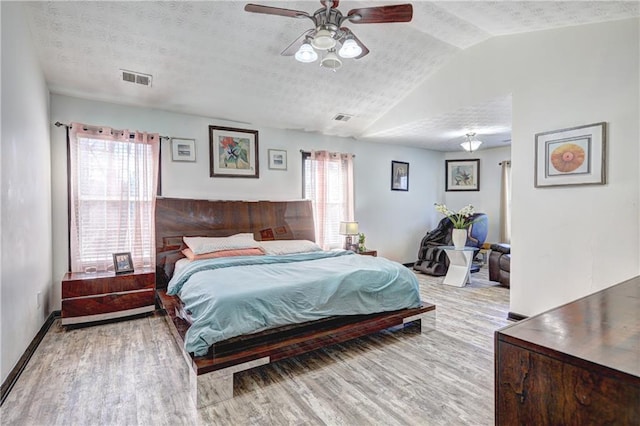 bedroom with visible vents, lofted ceiling, a textured ceiling, and wood finished floors