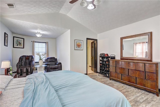 bedroom featuring visible vents, a textured ceiling, wood finished floors, and vaulted ceiling