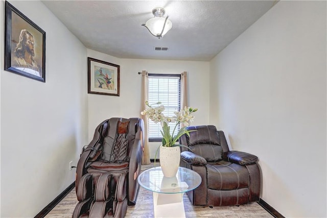 living area featuring baseboards, visible vents, and light wood-type flooring