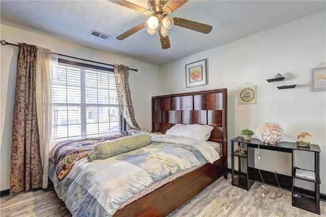 bedroom with visible vents, a textured ceiling, ceiling fan, and wood finished floors