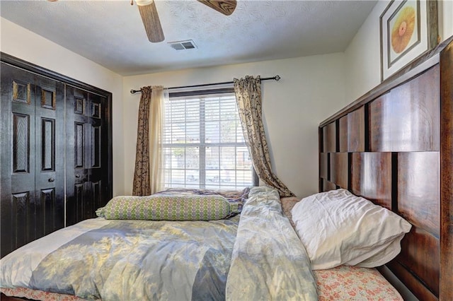 bedroom with ceiling fan, visible vents, a closet, and a textured ceiling