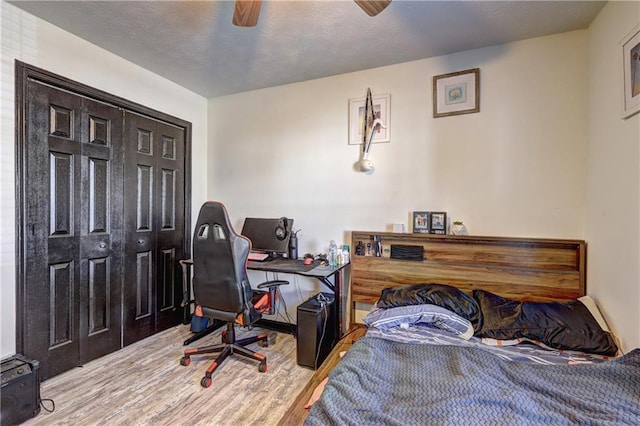 bedroom featuring ceiling fan, wood finished floors, and a textured ceiling