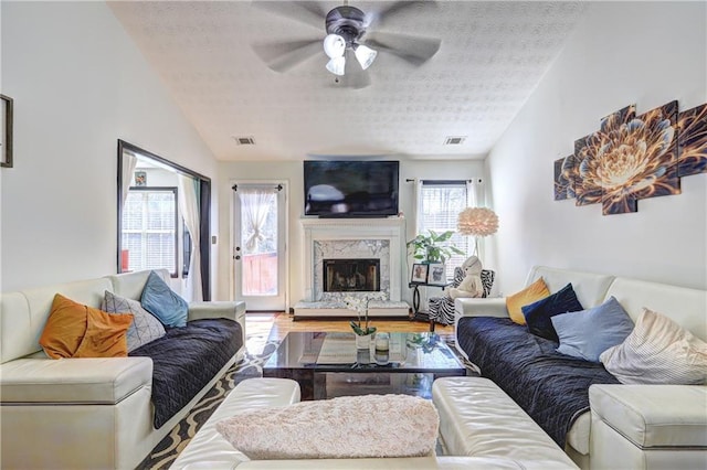 living room with visible vents, lofted ceiling, a textured ceiling, and a fireplace