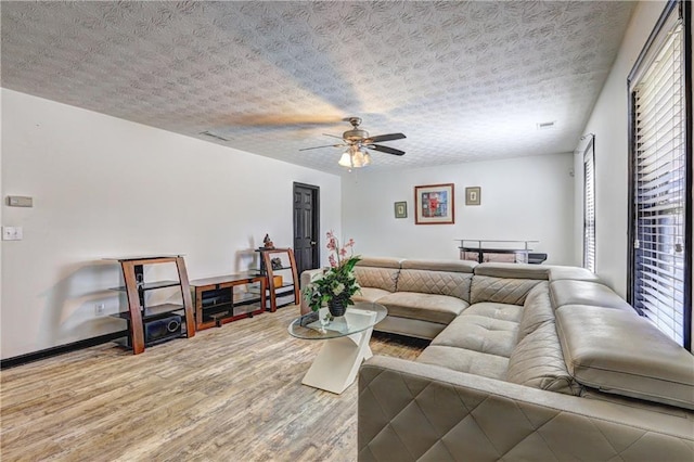 living area with visible vents, a ceiling fan, a textured ceiling, wood finished floors, and baseboards