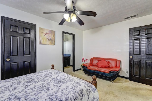 carpeted bedroom with visible vents, connected bathroom, a textured ceiling, and a ceiling fan