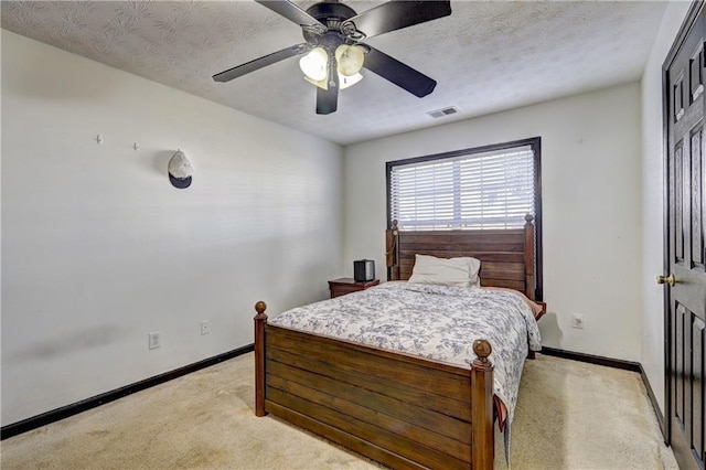 bedroom featuring baseboards, light colored carpet, and a textured ceiling