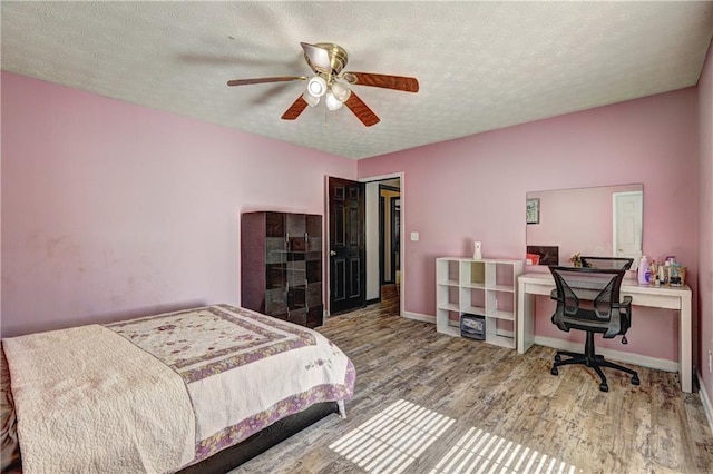 bedroom with ceiling fan, baseboards, a textured ceiling, and wood finished floors