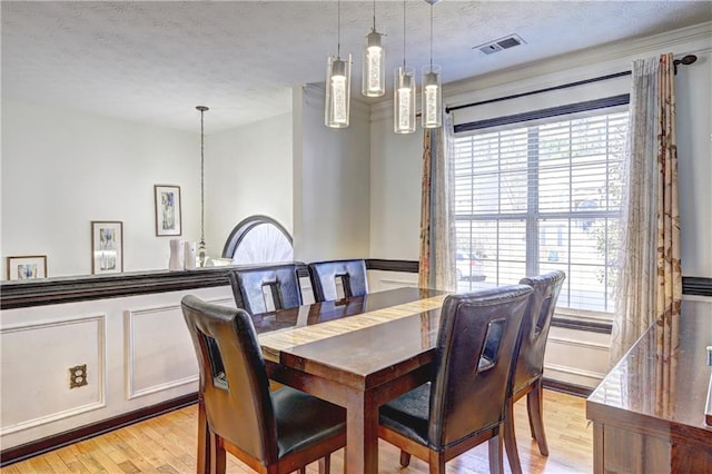 dining space featuring visible vents, a textured ceiling, and light wood-style floors