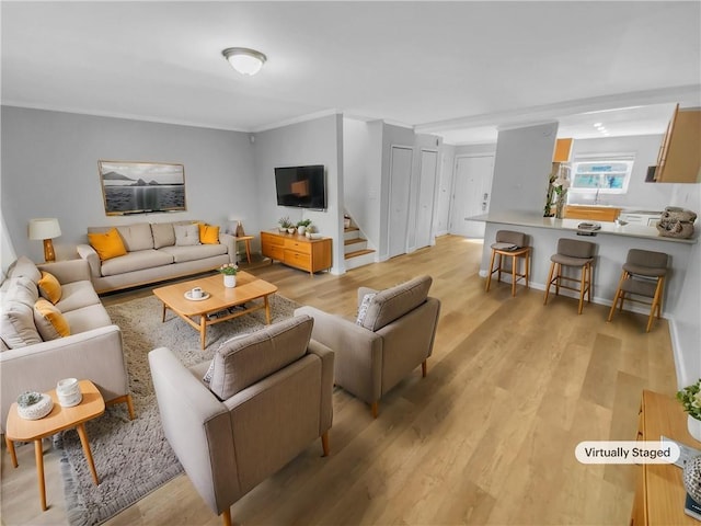 living area with light wood-style floors, ornamental molding, and stairway