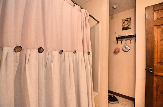 bathroom featuring tile patterned flooring, shower / bath combination with curtain, and a textured ceiling