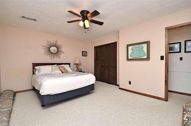 carpeted bedroom with a closet, a textured ceiling, and ceiling fan