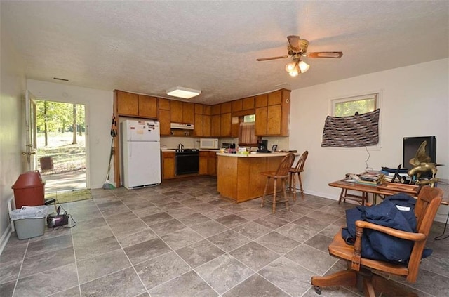 kitchen with kitchen peninsula, ceiling fan, white appliances, and a textured ceiling