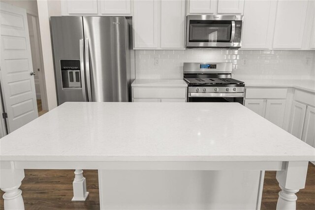 kitchen featuring tasteful backsplash, white cabinetry, stainless steel appliances, and dark hardwood / wood-style floors