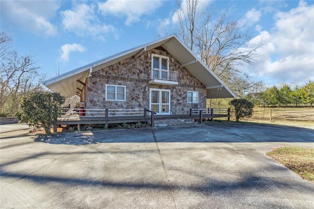 view of front of house featuring a balcony and stone siding