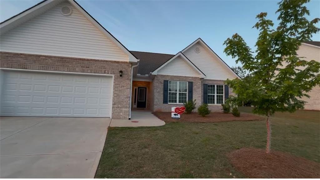 ranch-style house with brick siding, an attached garage, driveway, and a front yard