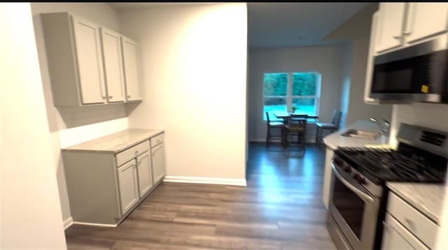 kitchen featuring light countertops, a sink, dark wood finished floors, and stainless steel appliances