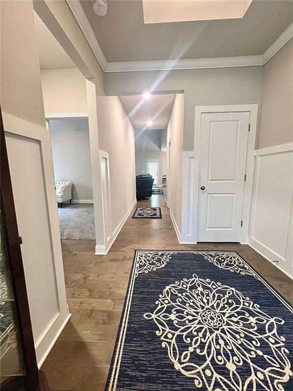 corridor with ornamental molding and hardwood / wood-style flooring