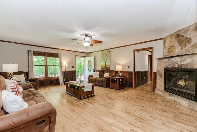 750 Jett Roberts Rd, Jefferson, GA 30549 - living room featuring a wainscoted wall, ornamental molding, light wood-style floors, ceiling fan, and a stone fireplace