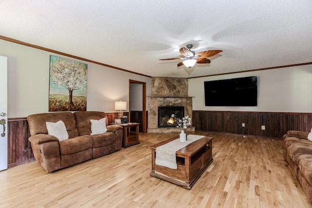 750 Jett Roberts Rd, Jefferson, GA 30549 - living room featuring crown molding, a ceiling fan, light wood finished floors, a wainscoted wall, and a stone fireplace