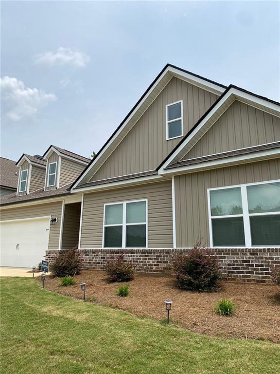 115 Harmony Farms Dr, Eatonton, GA 31024 - view of front facade with brick siding, a front yard, board and batten siding, concrete driveway, and an attached garage