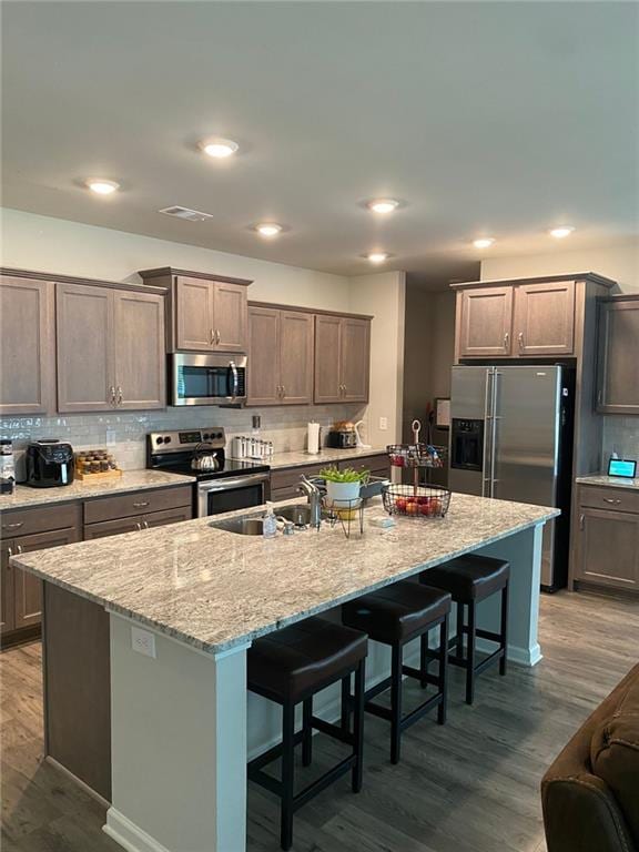 115 Harmony Farms Dr, Eatonton, GA 31024 - kitchen featuring stainless steel appliances, a kitchen bar, dark wood-type flooring, backsplash, and an island with sink
