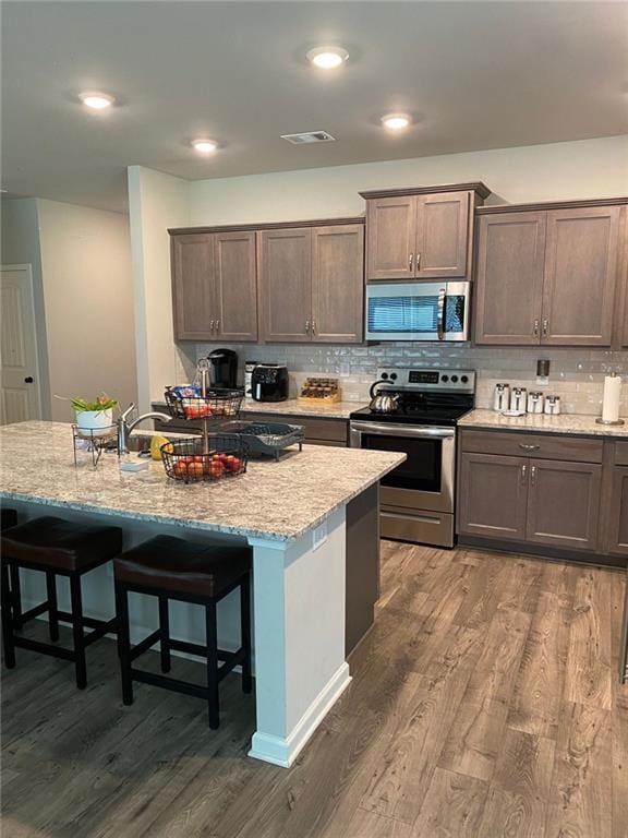 115 Harmony Farms Dr, Eatonton, GA 31024 - kitchen with appliances with stainless steel finishes, dark wood-type flooring, a kitchen breakfast bar, decorative backsplash, and recessed lighting