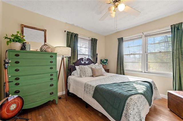 bedroom featuring a textured ceiling, wood finished floors, a ceiling fan, and baseboards