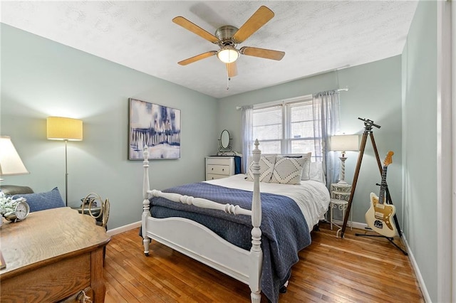 bedroom featuring a textured ceiling, hardwood / wood-style floors, a ceiling fan, and baseboards