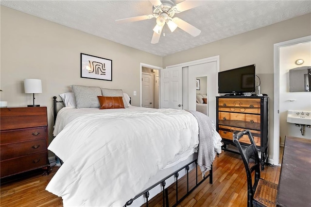 bedroom with a closet, ceiling fan, a textured ceiling, and wood finished floors