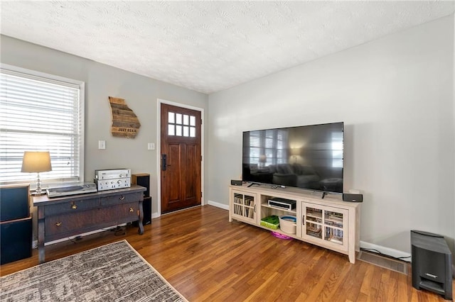 entrance foyer featuring a textured ceiling, baseboards, and wood finished floors