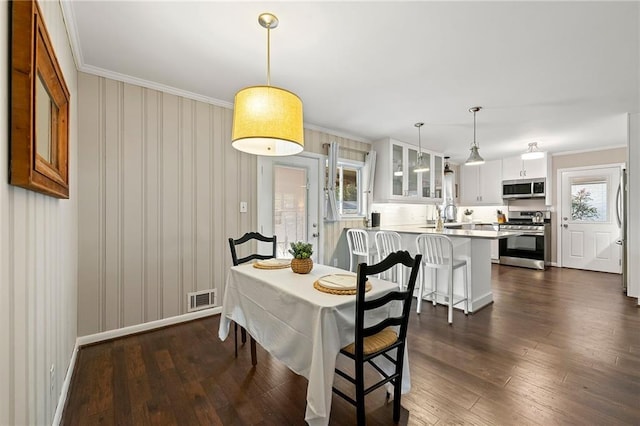 dining area featuring dark wood-style floors, plenty of natural light, visible vents, and crown molding