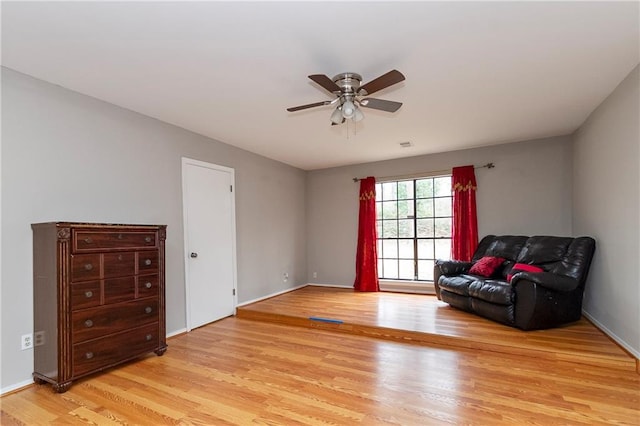 living area featuring visible vents, baseboards, light wood-style floors, and a ceiling fan