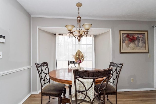 dining area featuring crown molding, wood finished floors, baseboards, and a chandelier