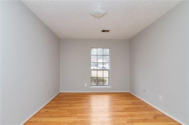 unfurnished room with visible vents, baseboards, a textured ceiling, and light wood finished floors