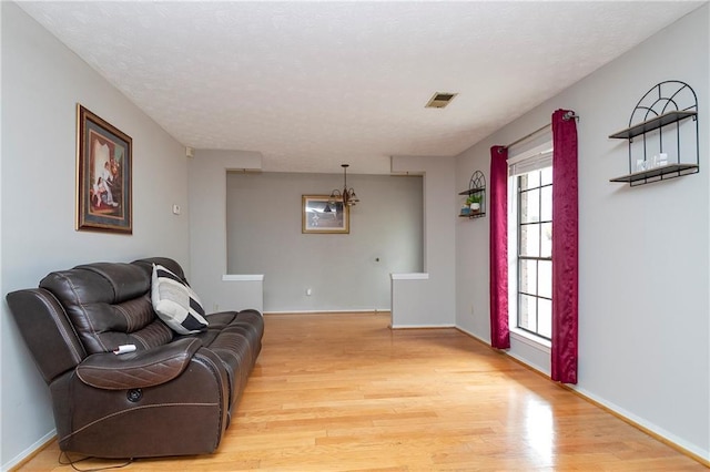 sitting room featuring baseboards, light wood-style floors, visible vents, and a textured ceiling