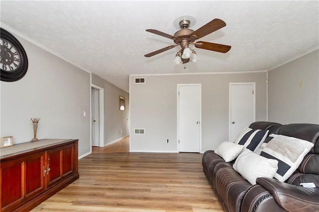 living room featuring light wood-style flooring, visible vents, and a textured ceiling