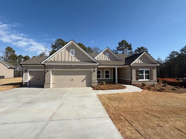 craftsman-style house with a garage, driveway, board and batten siding, and brick siding