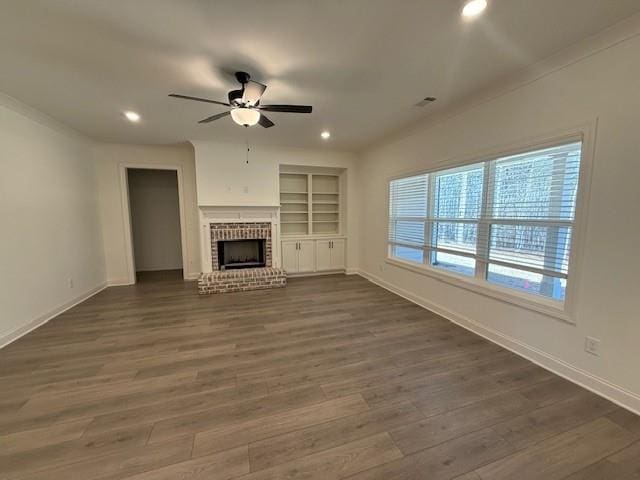 unfurnished living room with built in features, a fireplace, recessed lighting, dark wood-type flooring, and ceiling fan